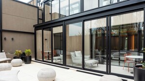 Un espace extérieur moderne, aménagé avec des jardinières en pierre, un mur de verre et un mobilier contemporain.
