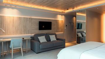 A modern bedroom with a bed, a gray sofa, a desk, and a mirror.