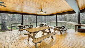 Une terrasse en bois avec des tables de pique-nique donnant sur un lac.