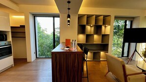 A modern kitchen with wooden cabinets, a central island, and a dining area with a chair and table.