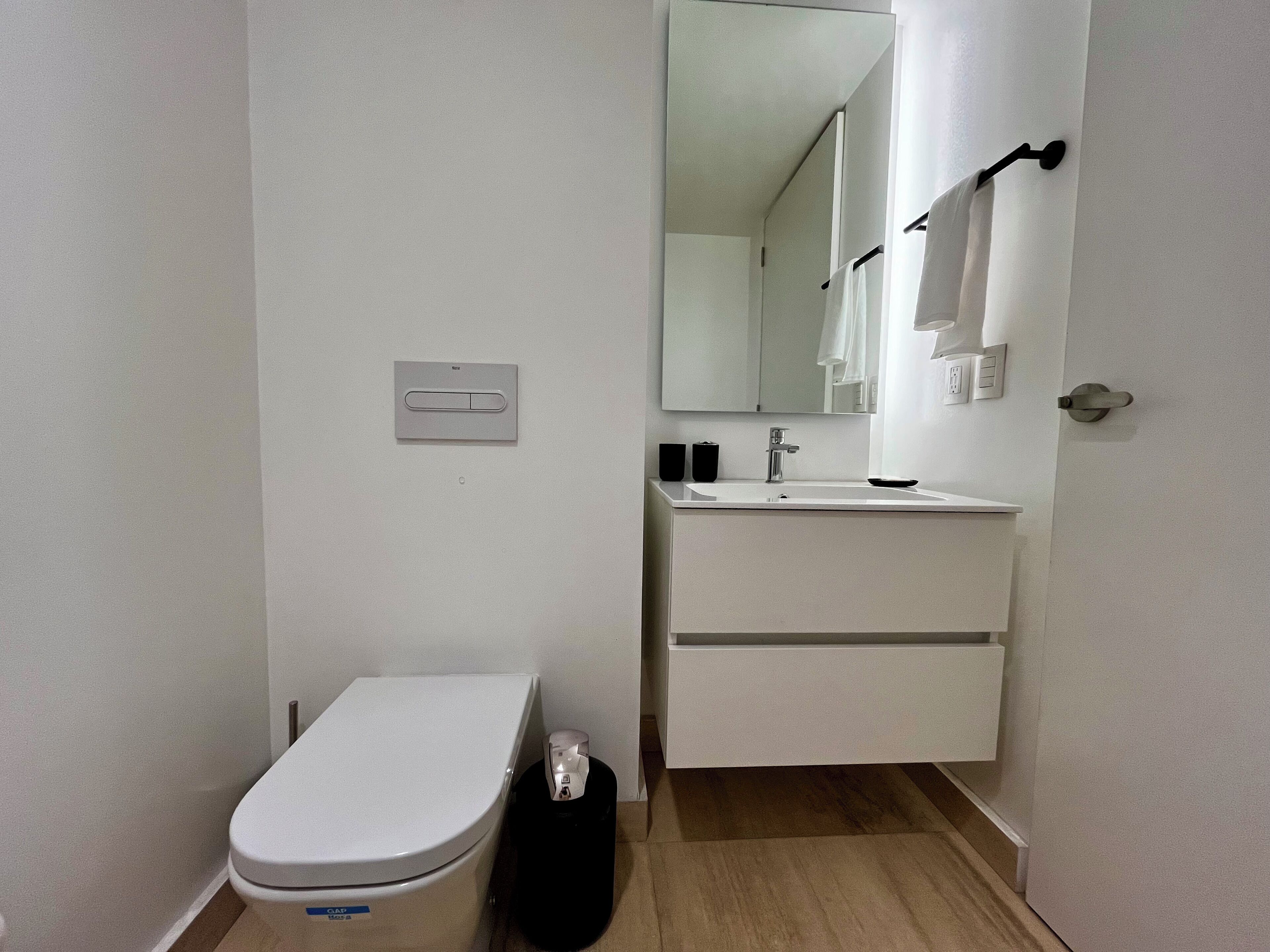 Et lille badeværelse med toilet, vask og spejl.