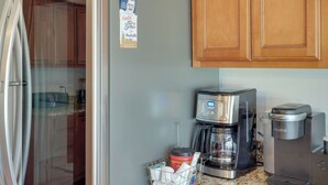 Een keuken met houten kastjes, een roestvrijstalen koelkast, een koffiezetapparaat en een Keurig koffiemachine.