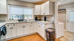 A kitchen with white cabinets, a sink, a stove, and a trash can. - Home 14 Mi to Highpoint Health w/ Fenced Yard! (Hendersonville)