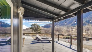 Eine überdachte Terrasse im Freien mit Holzboden, Metallgeländern und Bergblick.