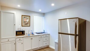 A kitchen with white cabinets, a stainless steel refrigerator, a microwave, and a window with blinds. - Hike & Explore: Studio Stay in Frazier Park (Frazier Park)