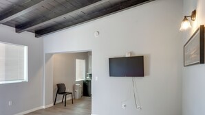 A room with a flat-screen TV mounted on the wall, a ceiling with exposed beams, and a window with blinds. - 6 Mi to Frazier Mountain: Cozy Studio Retreat (Frazier Park)