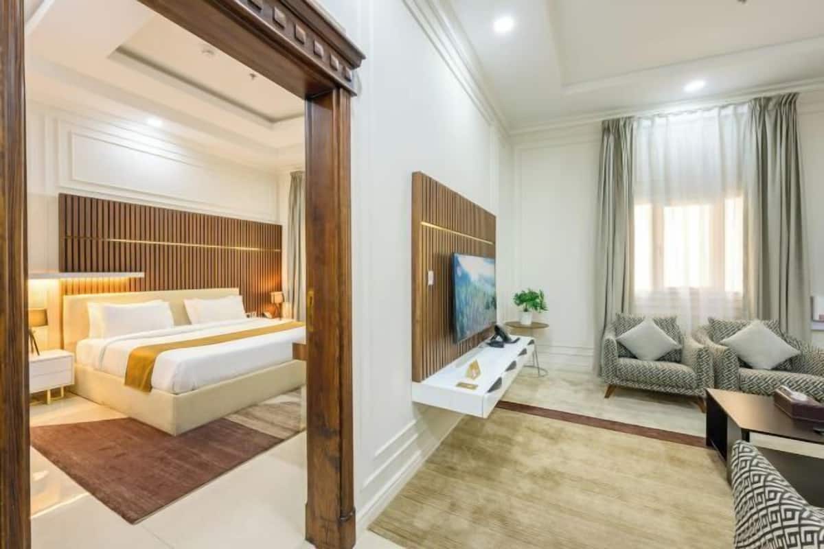 A modern hotel room with a bed, a sofa, a TV, and a small table.