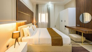 A modern hotel room with a large bed, bedside table, and a mirror. - Abraj INN Royal Hotel (Doha)
