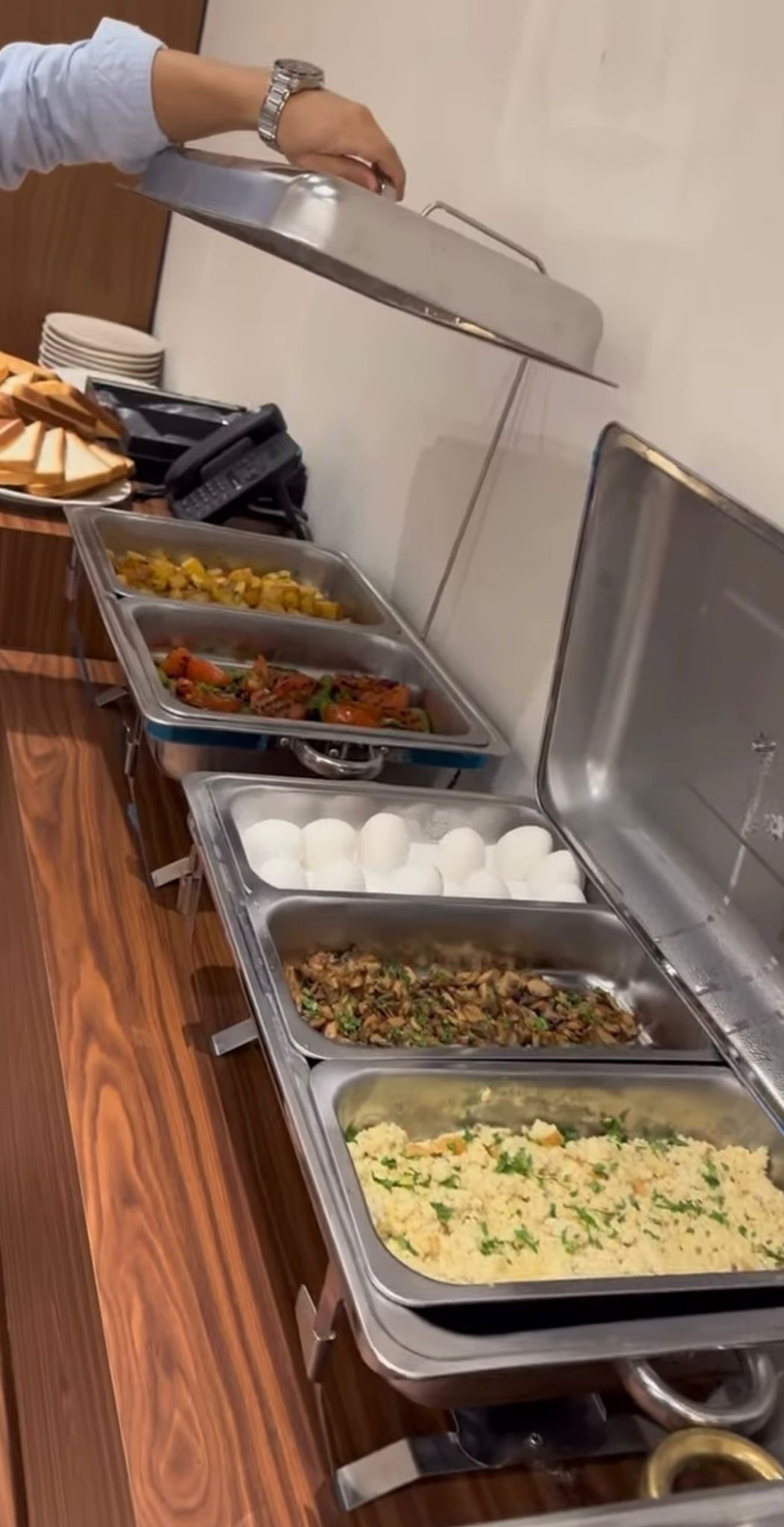 A buffet setup with various food items in metal containers, including eggs, rice, and salads.