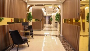 A modern hotel lobby with a reception desk, seating area, and a hallway leading to the rooms. - Abraj INN Royal Hotel (Doha)