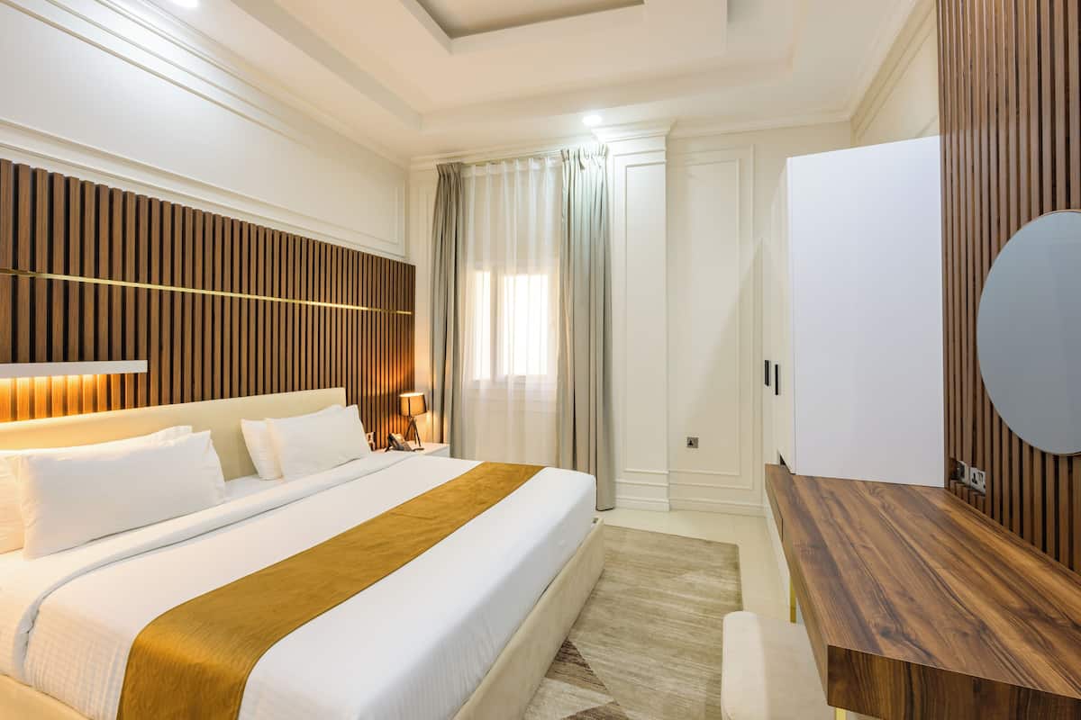 A hotel room with a large bed, a wooden headboard, a desk, and a mirror.