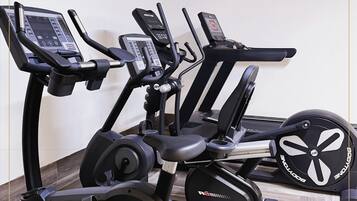 Un gimnasio con bicicletas estáticas y cintas de correr.