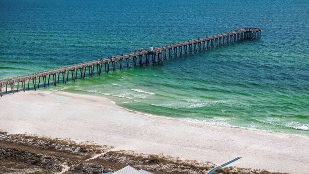 A pier extending into the ocean with a beach in the foreground.