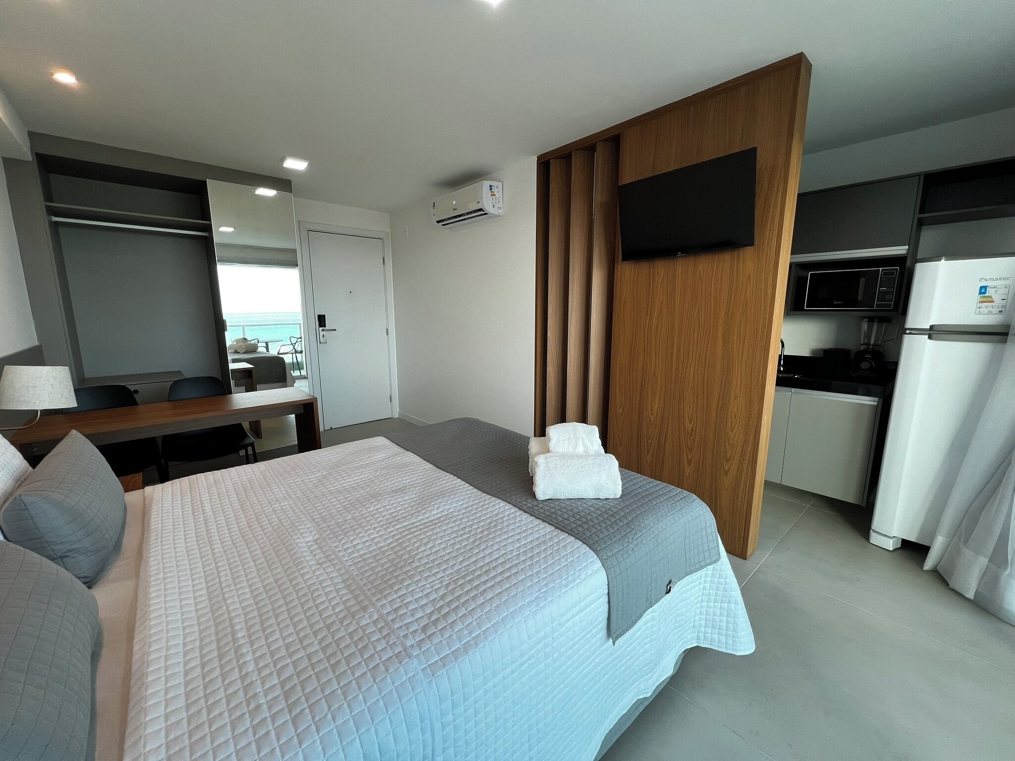 Camera d'albergo con un letto, una scrivania, una sedia, una televisione, angolo cottura e vista mare.