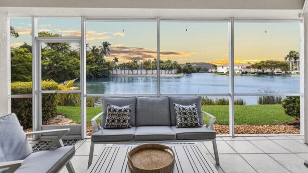 A modern outdoor seating area with a view of a lake and sunset.