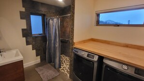 Une petite salle de bain comprenant une douche, un lavabo et une petite fenêtre.