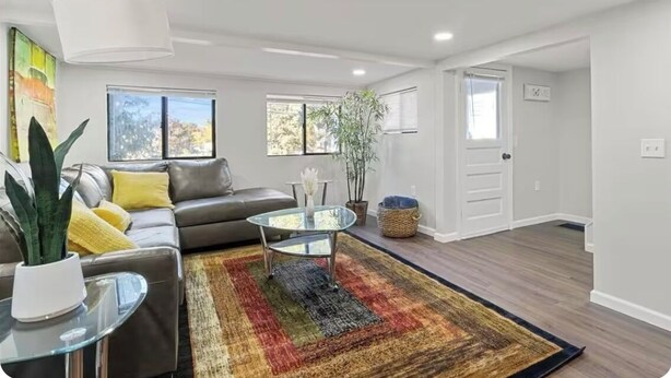 A modern living room with a leather sofa, glass coffee table, and a colorful rug.