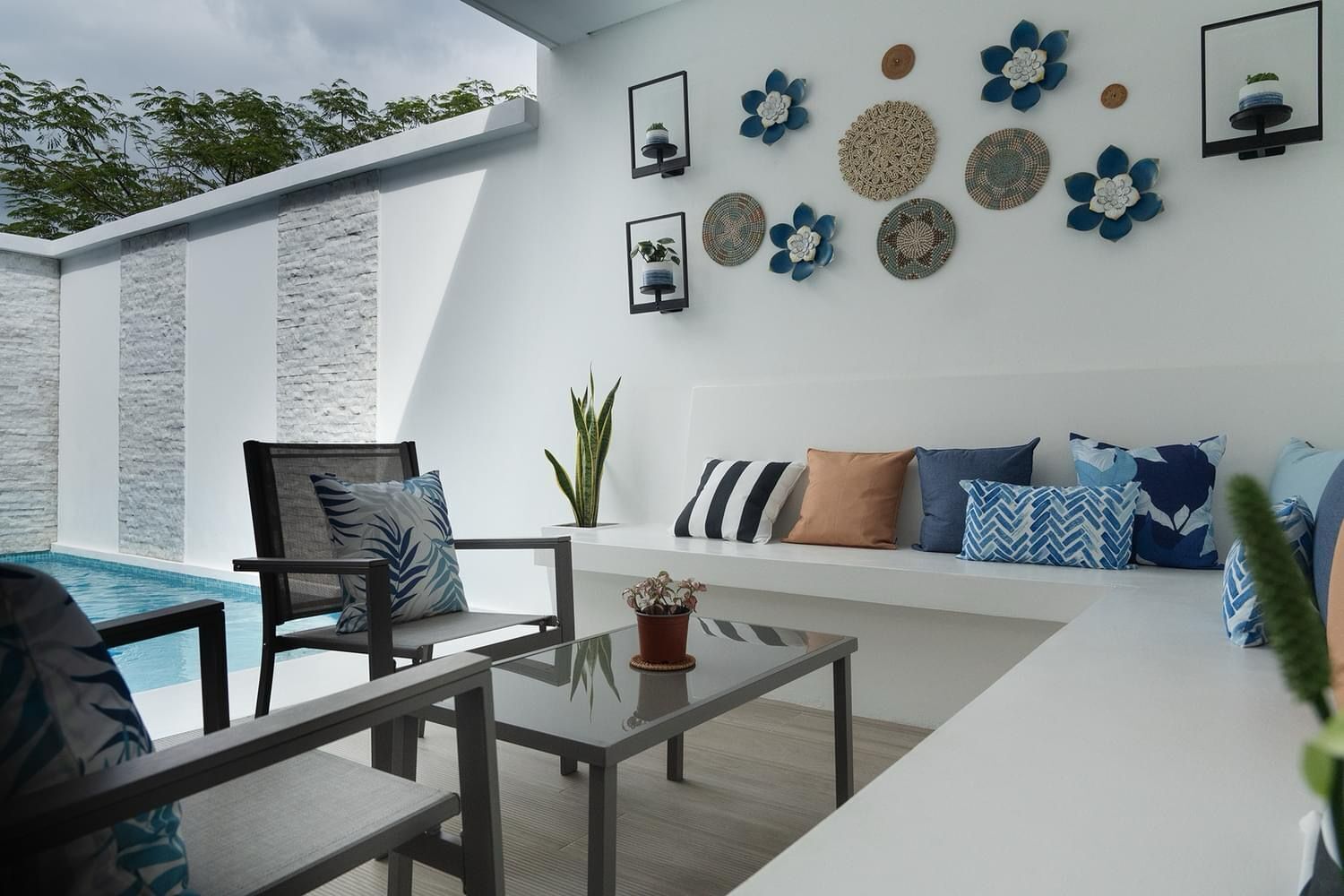 A modern outdoor seating area with a pool, a glass table, and a variety of decorative wall art.