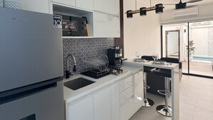 Una cocina moderna con refrigerador incorporado, cafetera y un comedor con taburetes de bar.
