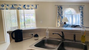 A kitchen with a double sink, a kettle, and a bottle of hand sanitizer. - Near Beach-3br-sleeps6-patio-garden-parking-ac (Edgewater)