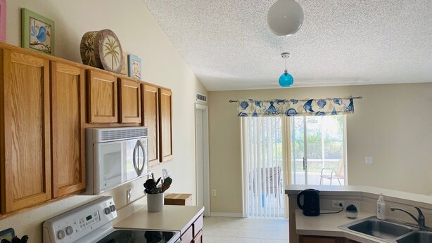 A kitchen with wooden cabinets, a stainless steel refrigerator, a stove, and a sink. - Near Beach-3br-sleeps6-patio-garden-parking-ac (Edgewater)