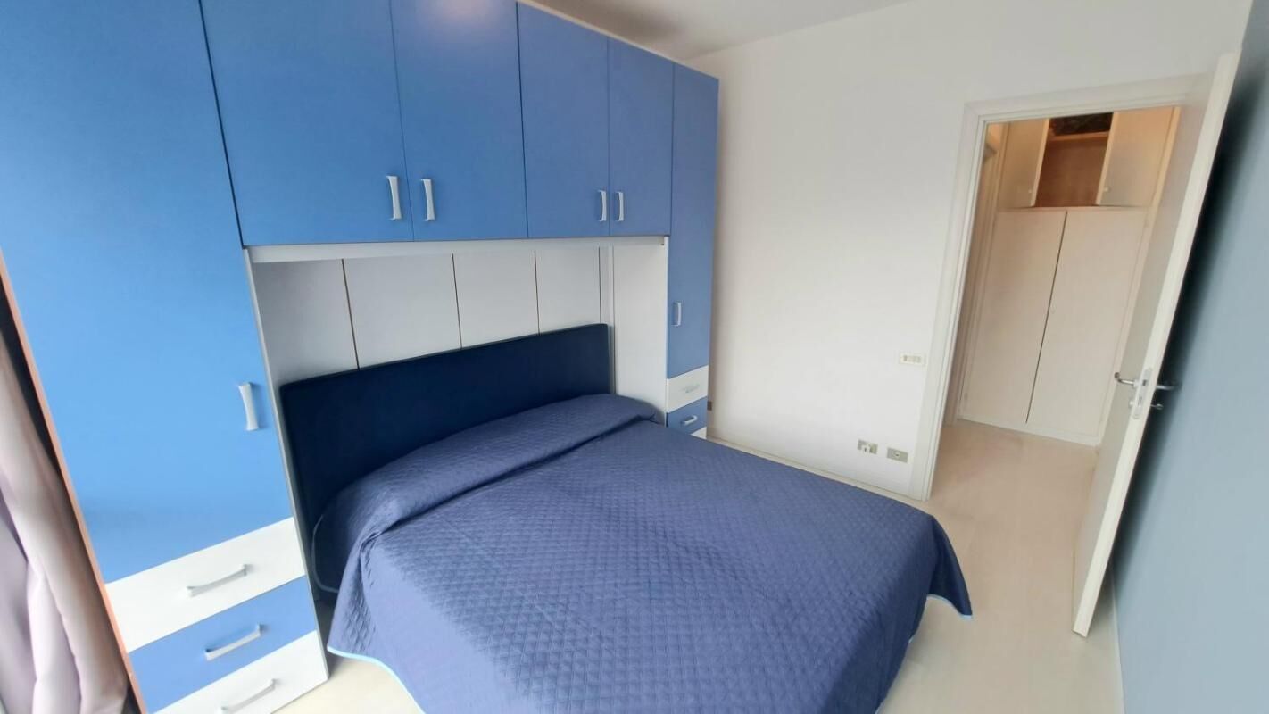 Une chambre à coucher comprenant un lit, une armoire et une porte donnant sur une autre pièce.