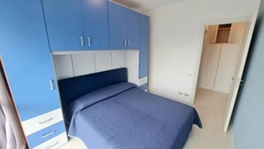 A bedroom with a bed, a wardrobe, and a door leading to another room. - Casa Maruzza - in the Centre of Cefalù (Cefalù)
