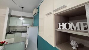 A modern kitchen with white cabinets, a built-in oven, and a teal accent wall. - Casa Maruzza - in the Centre of Cefalù (Cefalù)
