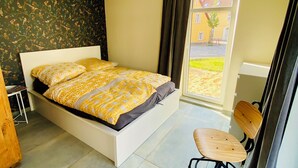 A bedroom with a bed, a desk, and a chair. - The yellow house at the harbor (Wolgast)