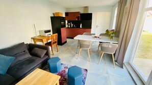A modern living room with a sofa, a wooden coffee table, and a dining area with a white table and chairs. - The yellow house at the harbor (Wolgast)