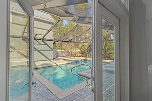 A swimming pool with a glass enclosure, a metal ladder, and a tiled deck. - Barefoot Bliss | 5BR | Screened-in Pool & Spa! Carriage House! Walk to Beach! (Santa Rosa Beach)