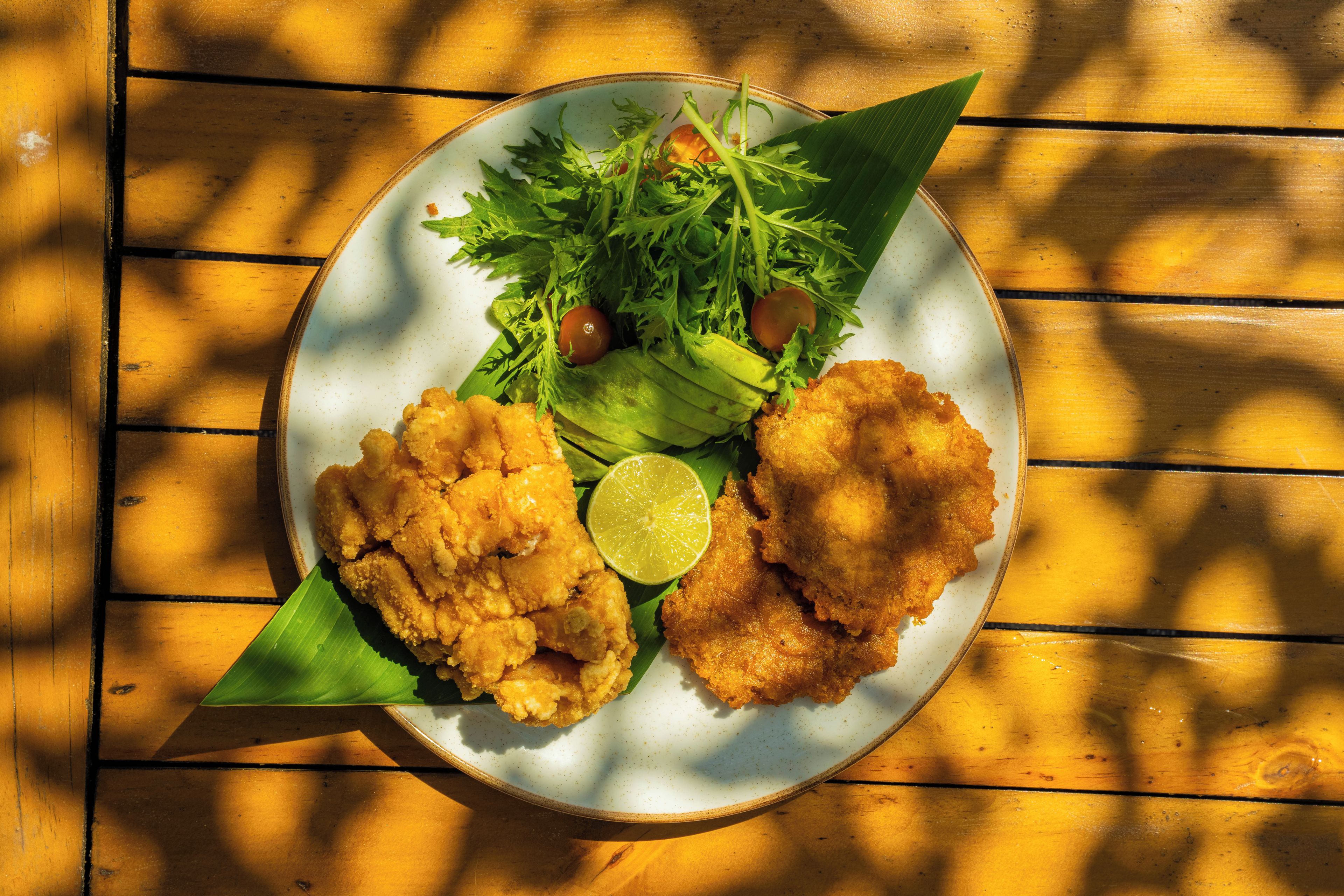 Un plato con comida frita y verduras sobre una mesa de madera.
