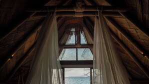 A room with a bed, a view of the sea, and a thatched roof. - Isla Corona (Rosario Islands)