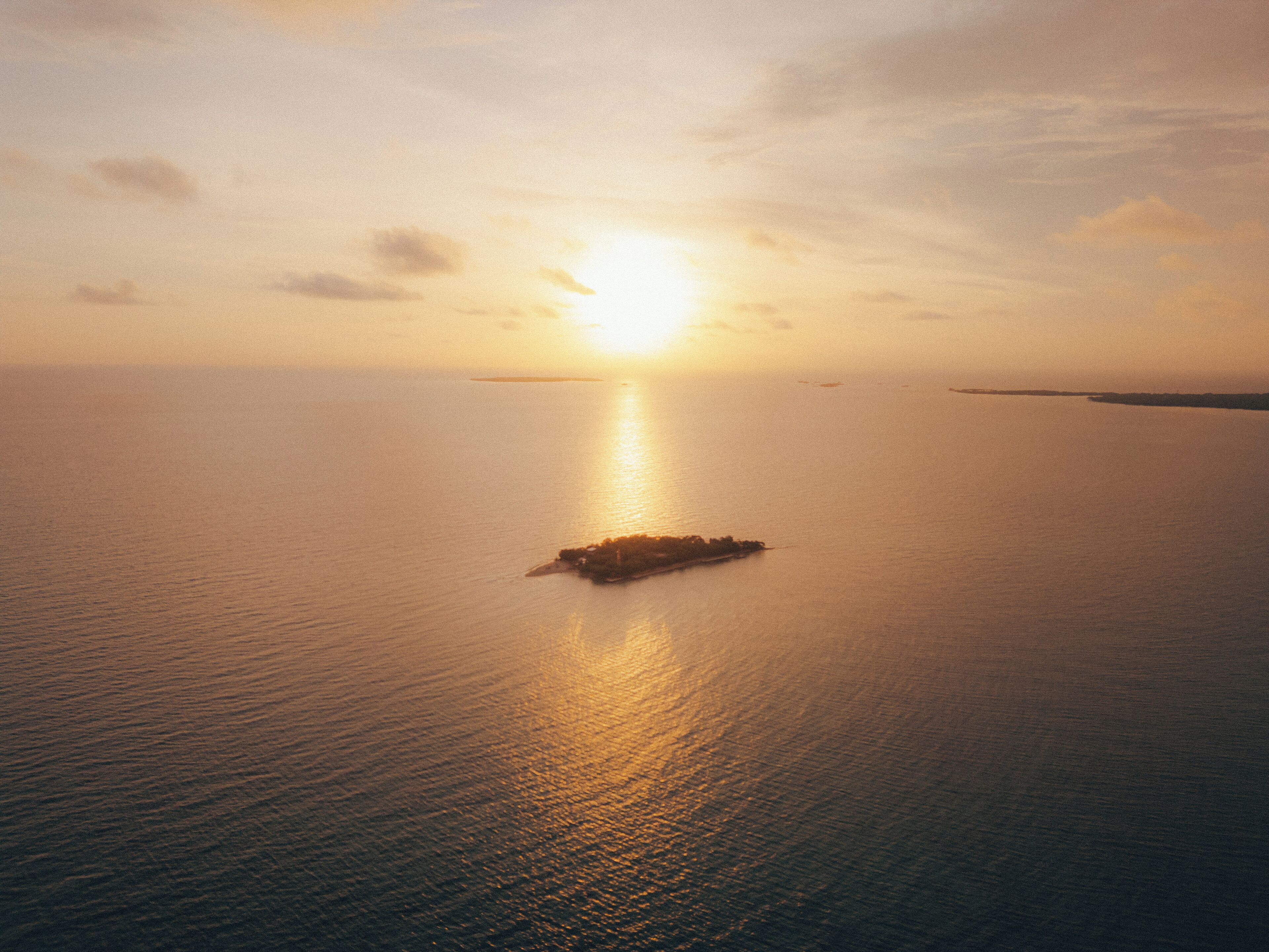 Ruhige See mit einer kleinen Insel in der Mitte, die das Sonnenlicht reflektiert.