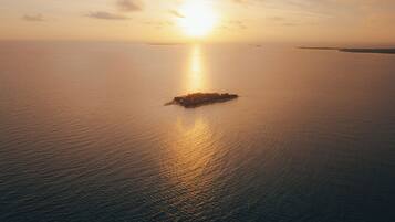 A calm sea with a small island in the center, reflecting the sunlight.