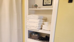 A white cabinet with folded towels and a framed sign that says "HOME is where your story begins." - Retro themed 2-bedroom house in Boone The Retro Rambler is pet friendly! (Boone)