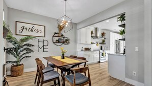 A modern kitchen with white cabinets, a central island, and a dining area with a wooden table and chairs.