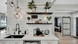 A modern kitchen with a coffee bar, white cabinetry, and a dishwasher.