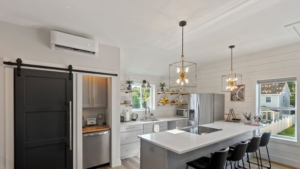 A modern kitchen with a central island, bar stools, and pendant lighting.