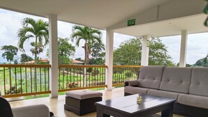 A spacious balcony with a sofa, chairs, and a coffee table. - Colina del Sol Hotel Hacienda (Quimbaya)