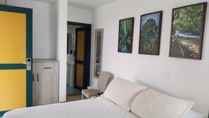 A hotel room with a bed, a chair, a wardrobe, and a bathroom visible through an open door. - Colina del Sol Hotel Hacienda (Quimbaya)