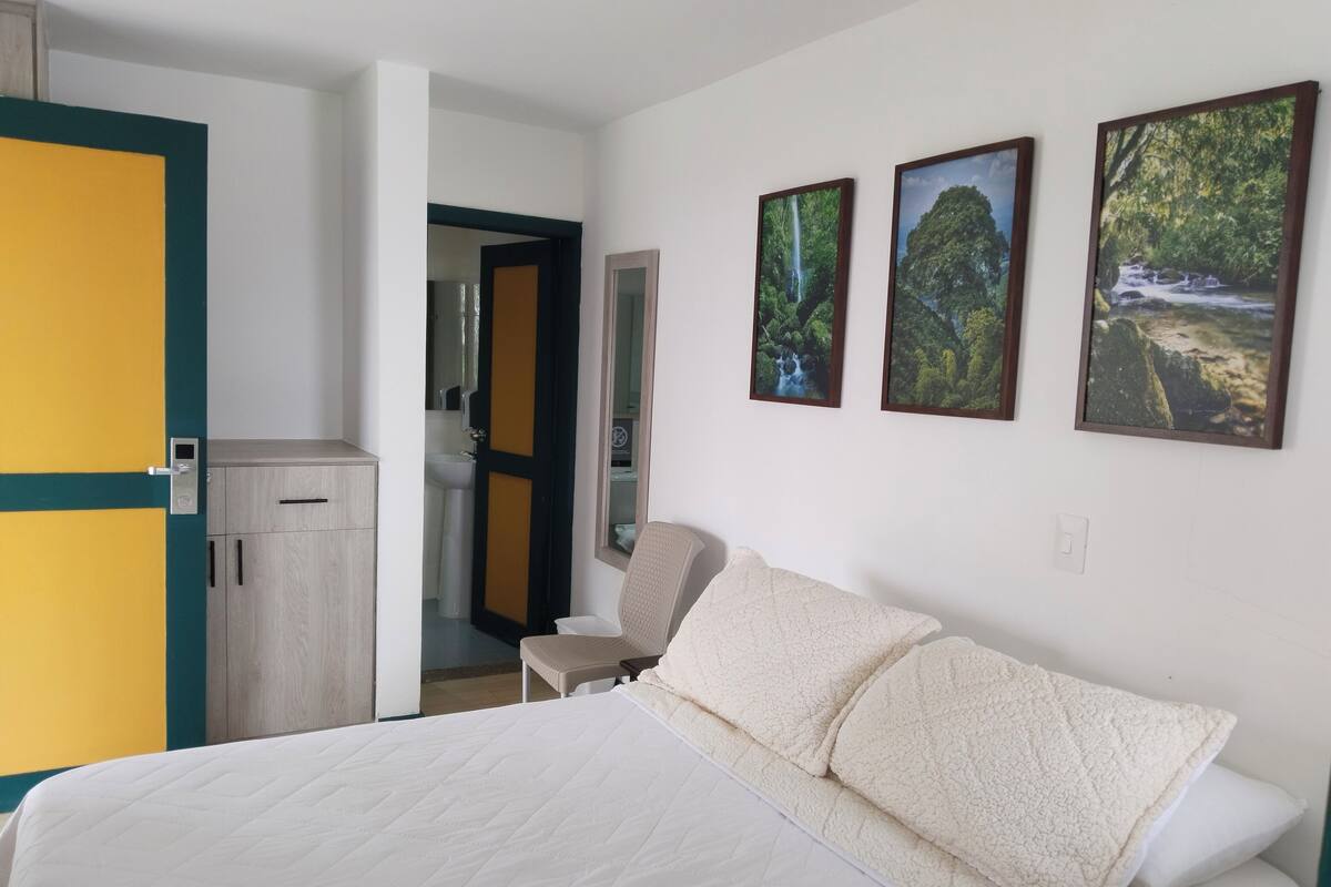 Een hotelkamer met een bed, een stoel, een kledingkast en een badkamer die door een geopende deur zichtbaar is.