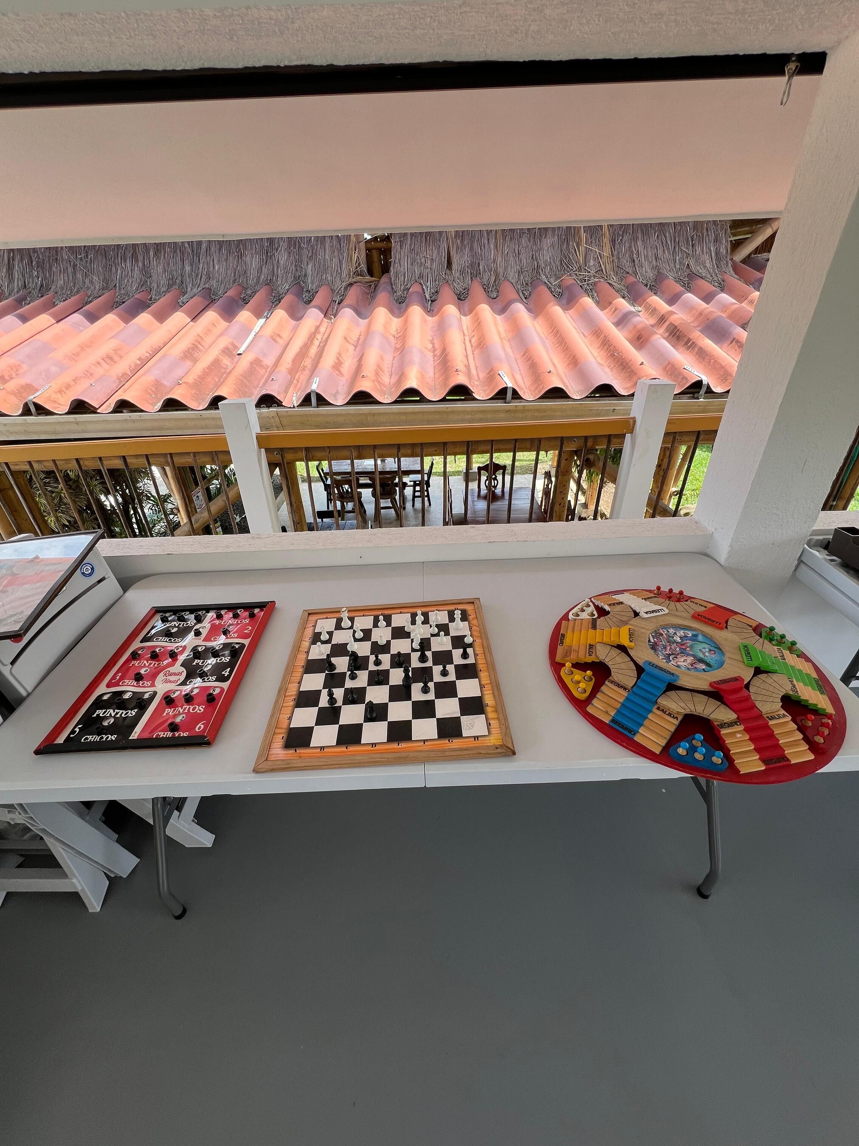 A table with three board games, a balcony with a tiled roof, and outdoor furniture.