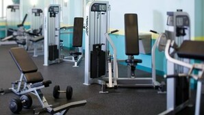 Un gimnasio con diversas máquinas de ejercicio, bancos y pesas.