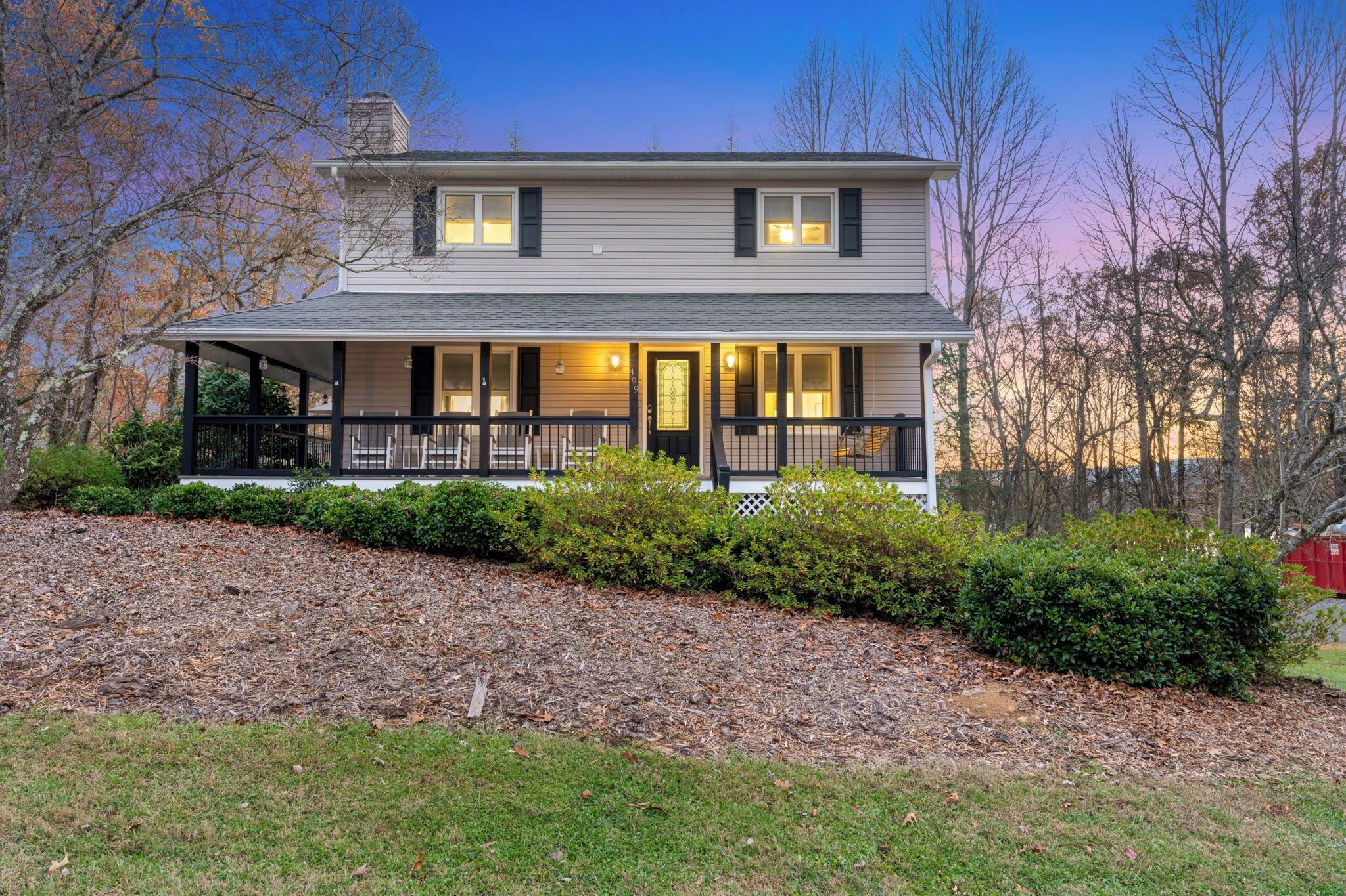 A two-story house with a front porch, a chimney, and a well-maintained lawn.