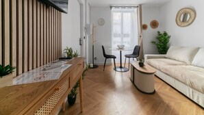 A modern living room with a wooden dining table, a sofa, and a small round table. - Le Serbie RdC - 4 rue de Serbie - Vichy (Vichy)