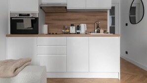 A compact kitchen with white cabinets, a built-in oven, and a wooden countertop. - Le Serbie RdC - 4 rue de Serbie - Vichy (Vichy)