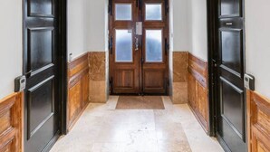 A hallway with two black doors, a wooden floor, and a white wall. - Le Serbie RdC - 4 rue de Serbie - Vichy (Vichy)