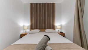 Hotelkamer met een groot bed, houten hoofdeinde, twee nachtkastjes met lampen en uitzicht op de nachthemel.