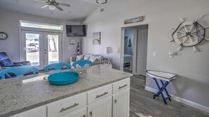 A modern kitchen with a large island, white cabinetry, and a blue chair.